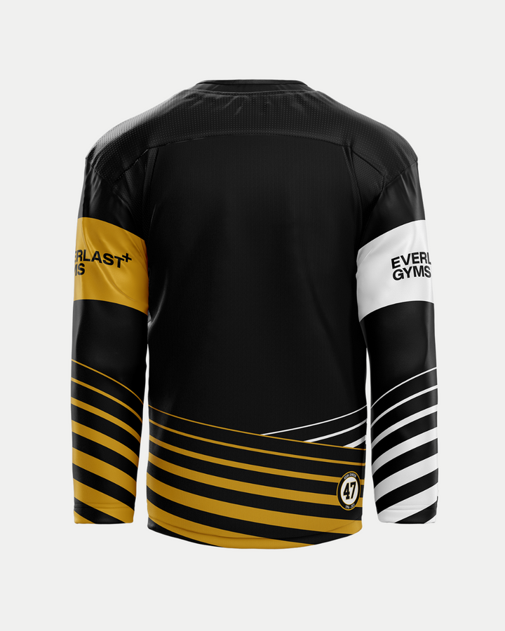 The Panthersland 2025/26 Classic Replica Home Warm-Up Jersey is a long-sleeved black top with gold and white diagonal stripes on the sleeves and lower back, EVERLAST GYMS text on one sleeve, and a circular 47 logo near the hem.
