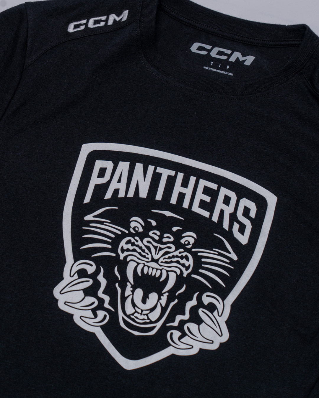 The Nottingham Panthers 25-26 CCM Black White Crest T-Shirt by Panthersland features a black design with a bold white shield logo, a roaring panther, and "PANTHERS" in large letters above the panther’s head.