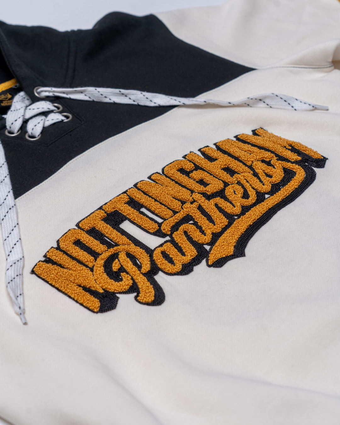 A close-up of the Panthersland Nottingham Panthers 25-26 Off White Script Hoodie, a fan favourite with cream and black panels, white laces, and yellow textured Nottingham Panthers embroidery.