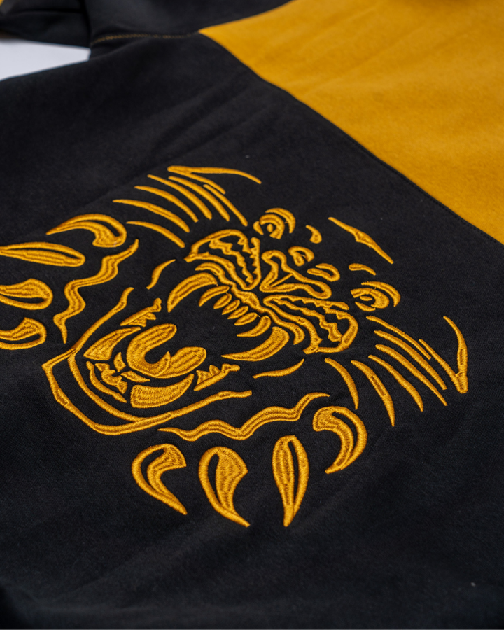 Close-up of the Panthersland Nottingham Panthers Claw Lace Hoodie 25-26 in black and yellow, featuring an embroidered roaring tiger face—a bold statement piece for fans.