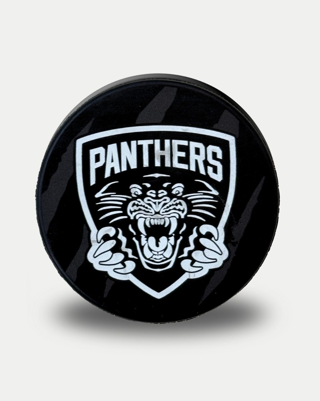 The Panthersland Nottingham Panthers 25-26 Black Claw Puck is a black hockey puck featuring a white shield logo with an aggressive panther head and "PANTHERS" above it.