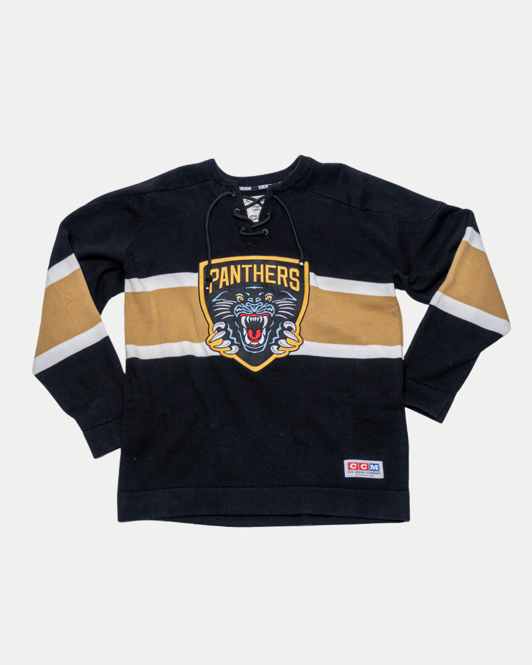 The Panthersland Nottingham Panthers 25-26 CCM Gold Heritage Sweater is a black jersey with tan and white stripes, featuring a large roaring panther head logo on the front and a small patch near the hem.