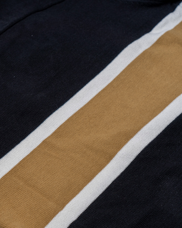 A close-up of the Nottingham Panthers 25-26 CCM Gold Heritage Sweater by Panthersland shows two white stripes flanking a single tan stripe on a black background.