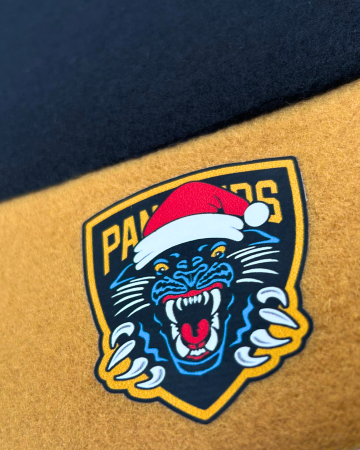 Celebrate the festive season in true Panthersland style with the Nottingham Panthers Santa Hat, featuring a snarling panther logo wearing a vibrant red Santa hat and “PANTHERS” displayed above—all printed on a striking yellow and black fabric background.