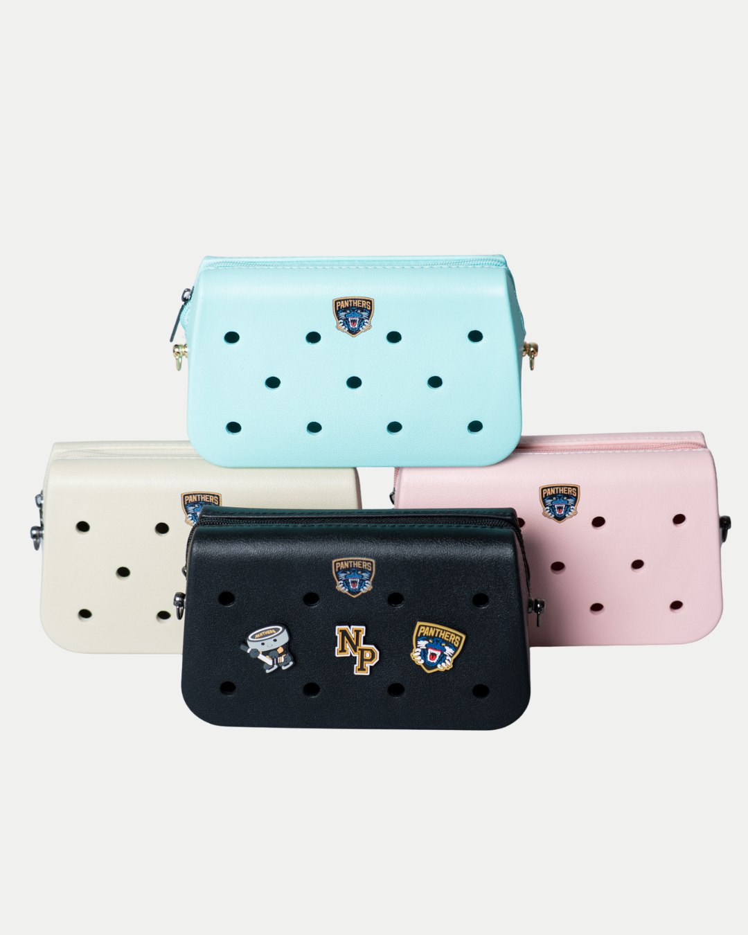 Four Nottingham Panthers Croc Charm Bags by Panthersland in pastel blue, cream, black, and pink, each with fun patches and pins, displayed on a plain white background.