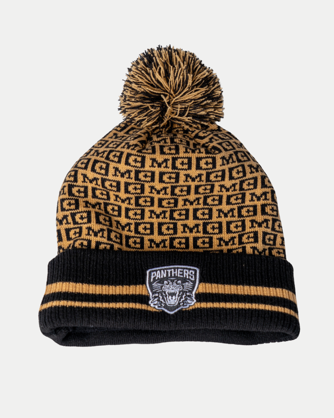The Nottingham Panthers 25-26 CCM Black Crest Pom Knit by Panthersland features a black and gold design with a pom-pom, repeating “M” pattern, black cuff with gold stripes, and a Panthers patch on the front.