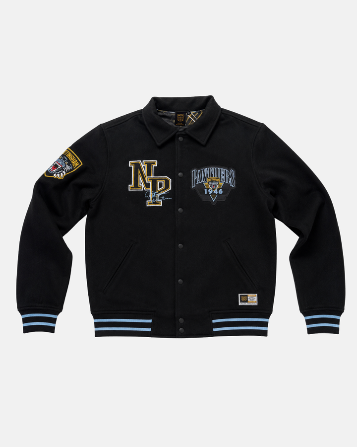 The Panthersland 26-27 Vintage Varsity Jacket is a black, vintage-inspired piece featuring blue and gold patches—such as “NP,” a distinctive Panthers crest with “Panthers 1994,” and a shield motif on the sleeve. This jacket is finished with blue-striped cuffs and hem, classic button closure, and two front pockets.