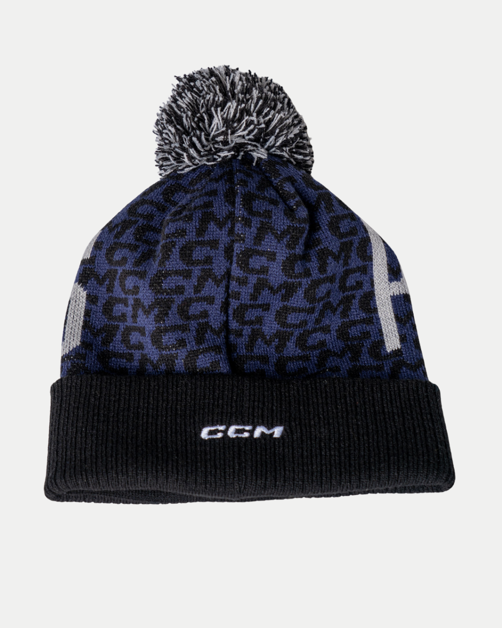 The Nottingham Panthers 25-26 CCM Blue Black Pom Knit by Panthersland is a navy and black beanie with a black and white pom-pom, a subtle pattern, and "CCM" embroidered in white on the cuff.