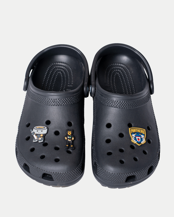 A pair of black clogs featuring two Panthersland Nottingham Panthers Logo Croc Charms attached to the shoe holes for a hockey-themed look.