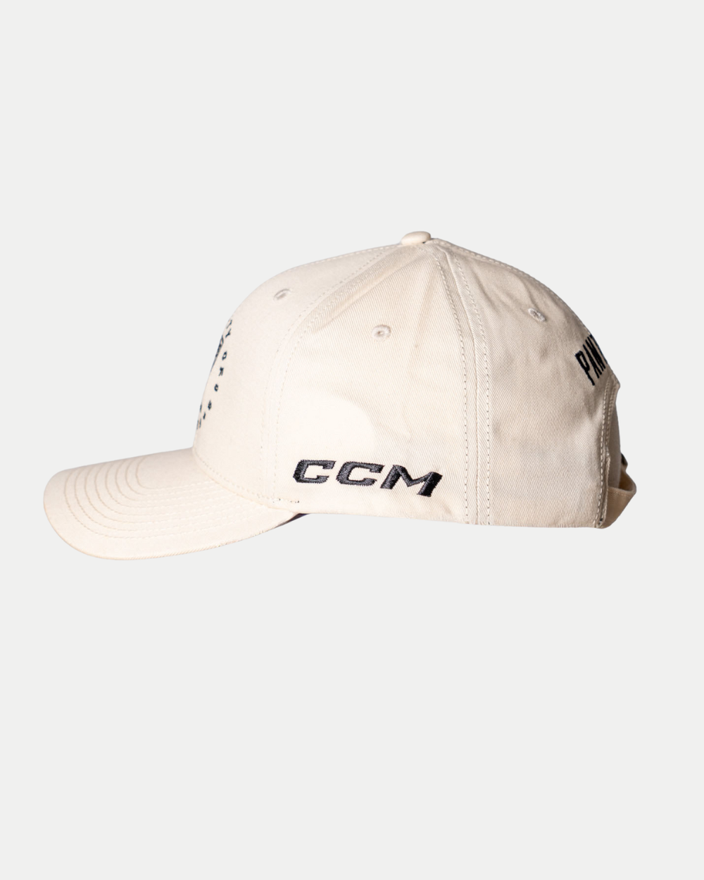 The Nottingham Panthers 25-26 CCM Cream Adjustable Cap by Panthersland is shown from the side, with black embroidered CCM text above the brim, extra black text on the side panel, visible stitching, and ventilation eyelets.