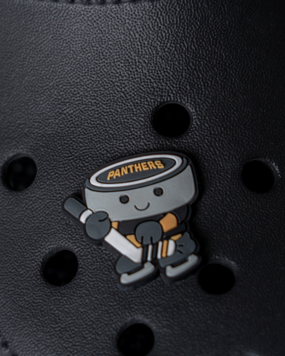 Show your team pride with the Nottingham Panthers 25-26 Puck Croc Charm by Panthersland—a cute cartoon hockey puck with "Panthers" on top and a stick, perfect for your black perforated shoes!.