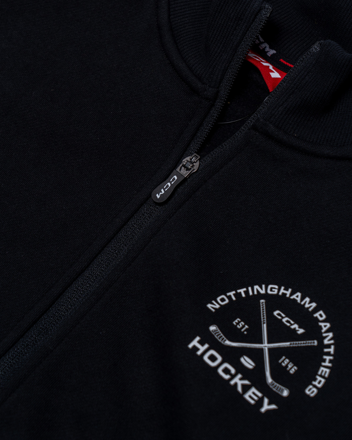 Close-up of a black Nottingham Panthers 25-26 CCM Track Jacket by Panthersland, featuring a white logo with crossed hockey sticks, "EST. 1946," and the CCM branding beneath the zipper.