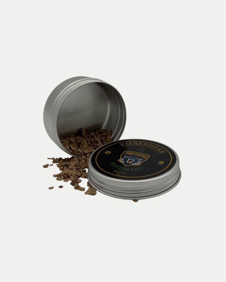 A round metal tin from the Nottingham Panthers Whiskey Smoker Kit by Panthersland lies on its side, spilling brown wood chips. The black lid features gold and green accents and reads: "Nottingham Panthers Whiskey Smoker Kit.