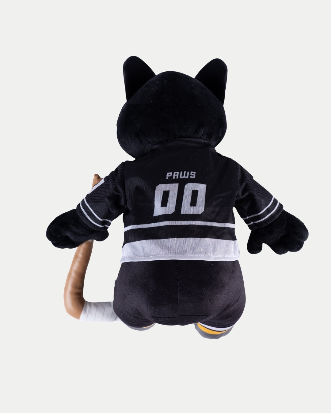 The Big Ice Skating Paws Plush by Nottingham Panthers sits with its back to the viewer, showing off a black jersey with “PAWS 00.” Its plush black fur contrasts with a tan, bandaged left leg.