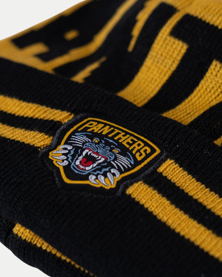 Close-up of the Nottingham Panthers 24-25 Black Team Pom Knit—black and gold knit fabric with a bold PANTHERS logo patch, featuring arched yellow text above an illustrated panther head baring its teeth.
