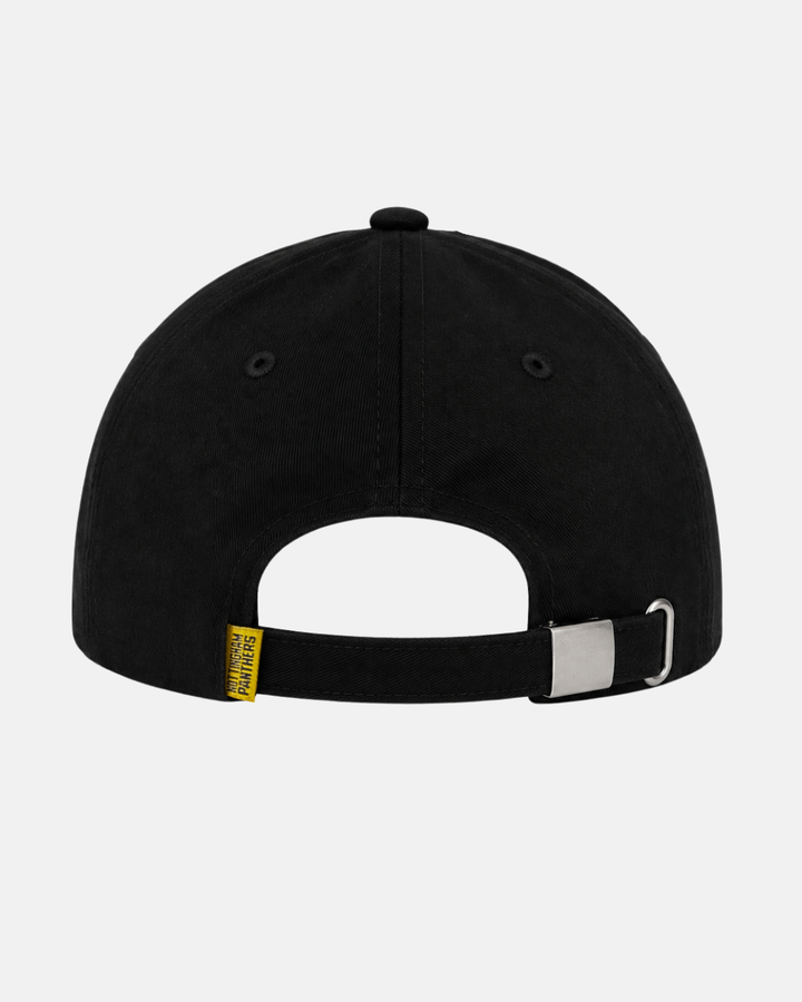 Back view of the Panthersland 26-27 Crest Dad Cap in black, featuring an adjustable strap with a metal clasp. A small yellow tag with text is attached near the strap, and an embroidered crest logo provides a subtle accent. The background is light gray.