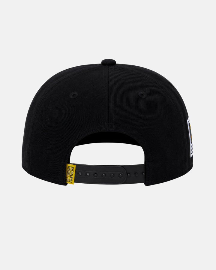 A rear view of the Panthersland 26-27 NP Logo Snapback is displayed, highlighting its adjustable strap and a small yellow tag on the left side. The background is plain and light gray.