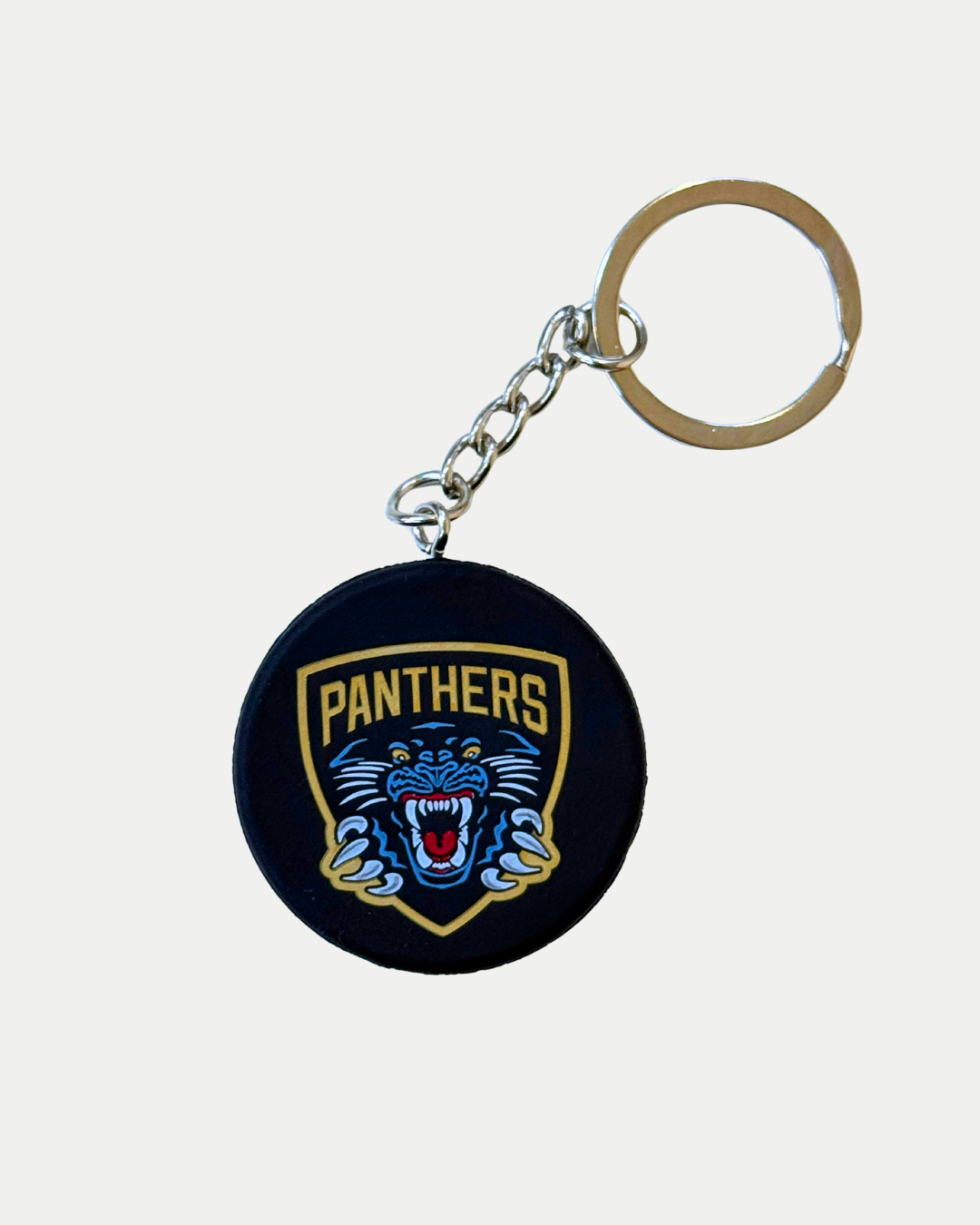 The Panthersland Nottingham Panthers Mini Puck Keyring features the team crest—a snarling panther head in a gold shield on black—attached to a metal ring.
