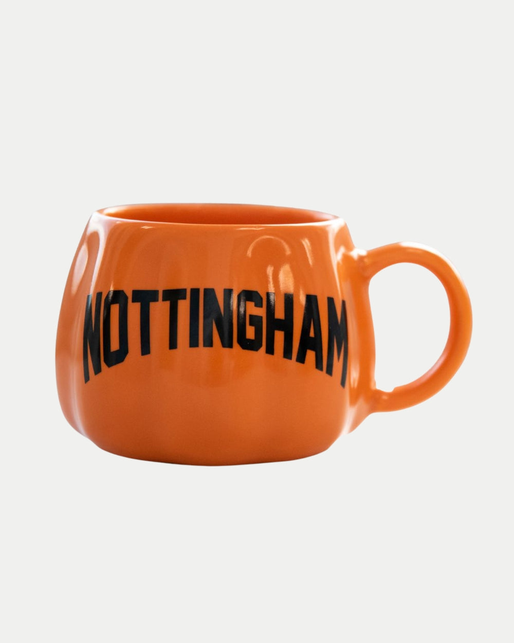 The Pumpkin Mug by The Nottingham Panthers features bold black NOTTINGHAM lettering, a round orange ceramic body with a large handle—ideal for enjoying pumpkin spice lattes.