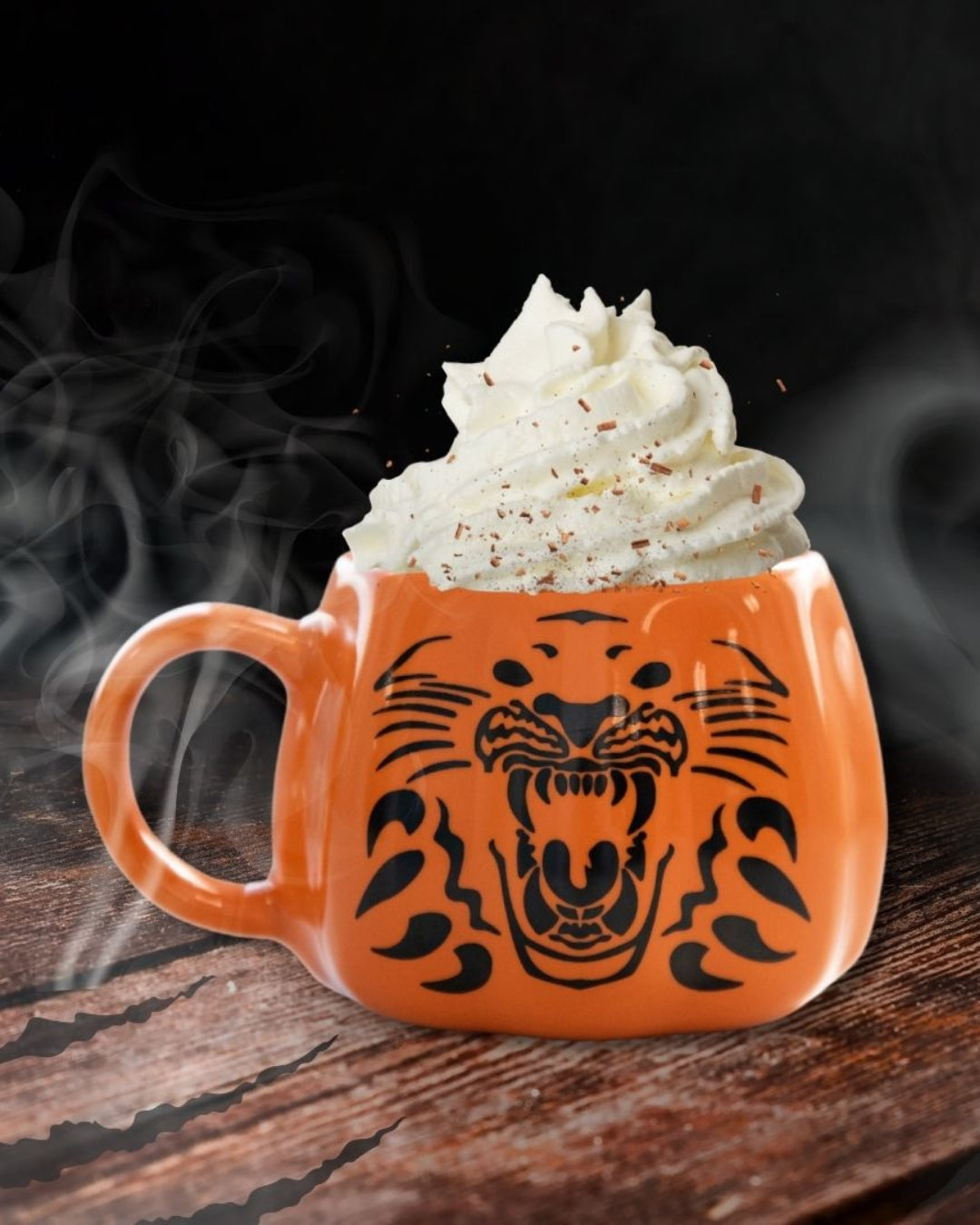 The Nottingham Panthers Pumpkin Mug, featuring a roaring tiger face, is filled with pumpkin spice and topped with whipped cream and chocolate shavings, steaming on a wooden surface against a dark background.