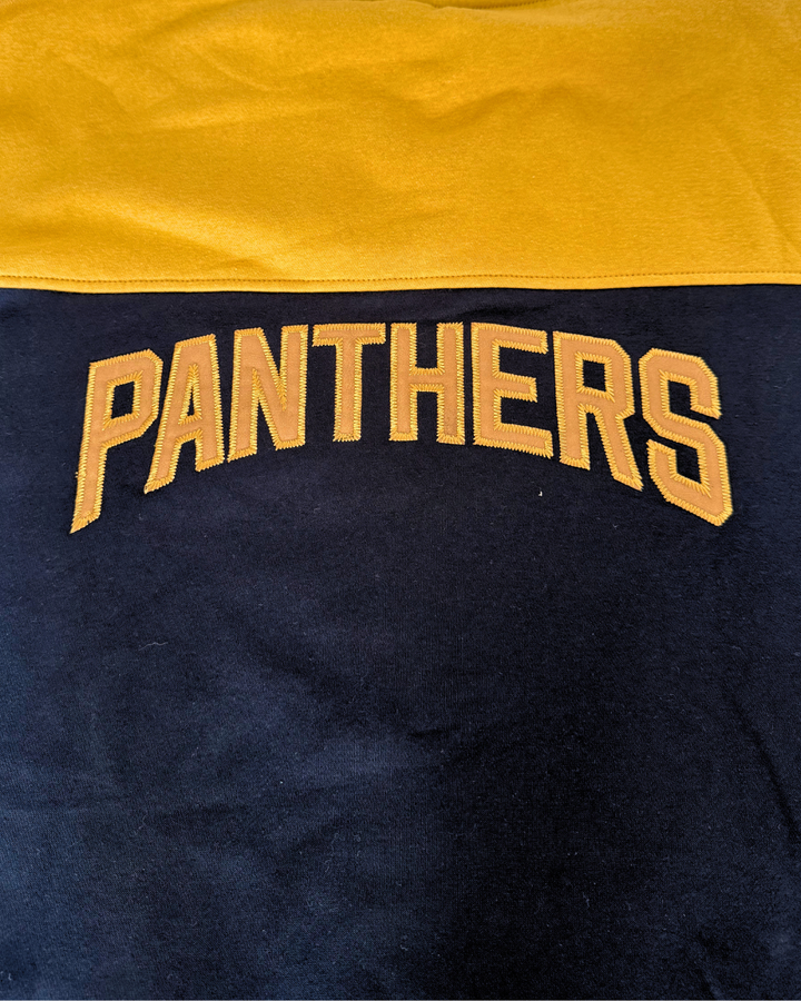 Sure! Here’s the rewritten sentence: The Panthersland 26-27 Gold Block Lace Hoodie features a gold upper section and black lower section, bold gold PANTHERS lettering across the center, and an embroidered NP logo for an authentic Nottingham Panthers touch.