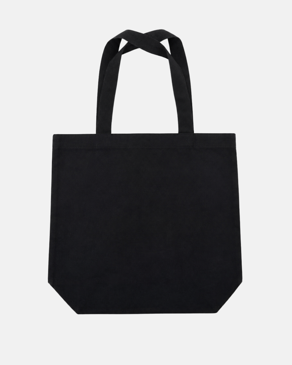 The 26-27 Puck Tote Bag by Panthersland is a plain black canvas tote with long handles, showcased against a white background. It features a simple, rectangular silhouette with subtly angled bottom corners.