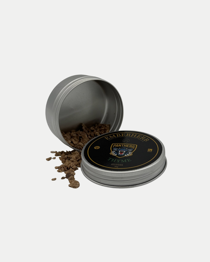 A silver metal tin labeled "Nottingham Panthers Whiskey Smoker Kit" by Panthersland lies open, spilling brown dried herbs onto a white surface, with its black lid featuring gold and green accents resting nearby—ideal for your cocktail smoker kit.
