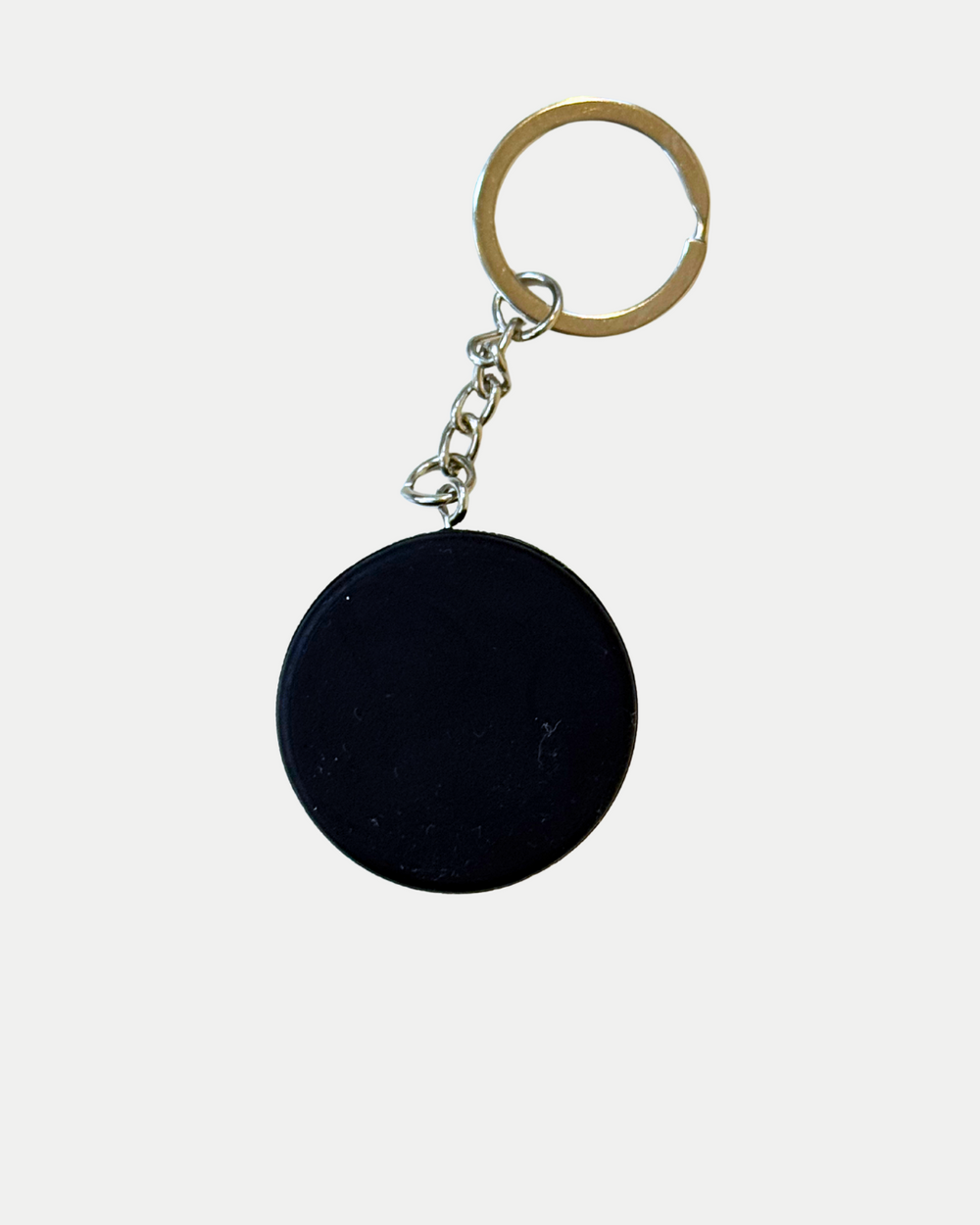The Panthersland Nottingham Panthers Mini Puck Keyring features a round, black mini puck with the team crest, attached to a short metal chain and gold key ring, displayed on a plain white background.