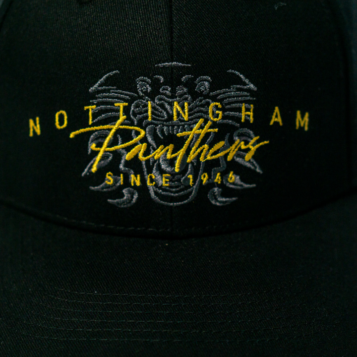 Close-up of the Panthersland Nottingham Panthers Signature Cap 25-26, featuring Since 1946 embroidered in yellow and white on black, with a panther face in the background. This adjustable cap is ideal for dedicated fans.