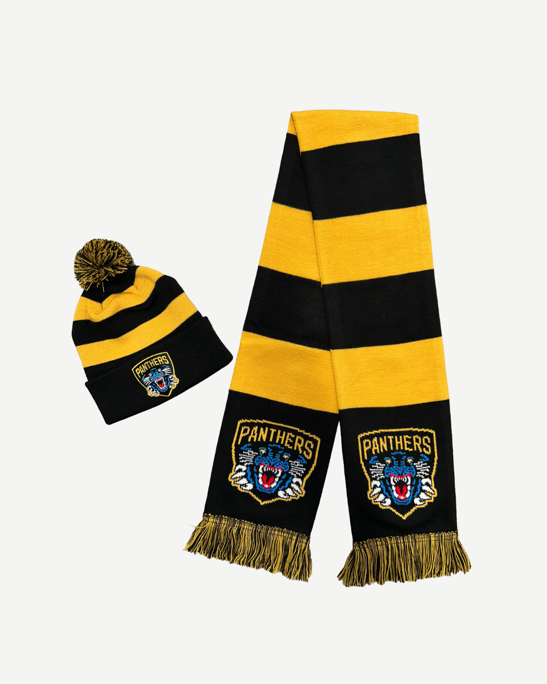 The Panthersland Nottingham Panthers Junior Hat & Scarf Set Gold includes a black and yellow striped scarf with fringes and “Panthers” logo, plus a matching pom-pom beanie with the same logo, displayed on a white background.