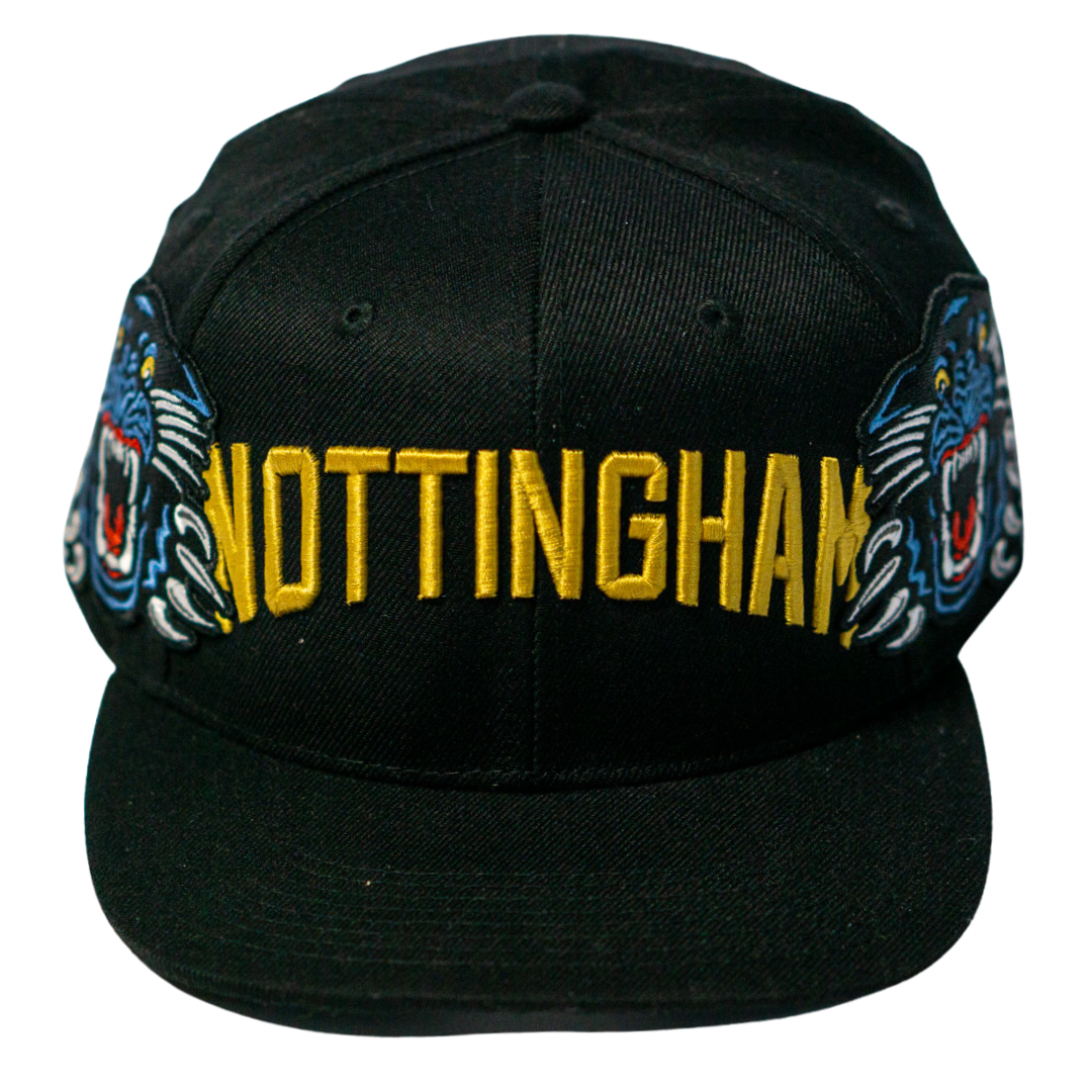 The Panthersland Nottingham Panthers 25-26 Big City Text Snapback Cap boasts bold yellow NOTTINGHAM embroidery and two blue tiger faces—an eye-catching addition to any collection.