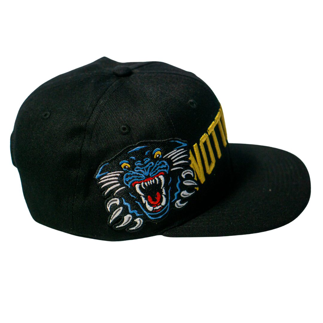 The Panthersland Nottingham Panthers 25-26 Big City Text Snapback Cap is a black cap with an embroidered blue, black, and white roaring panther and bold yellow VOTTO text on the side—ideal for fans and snapback collectors.