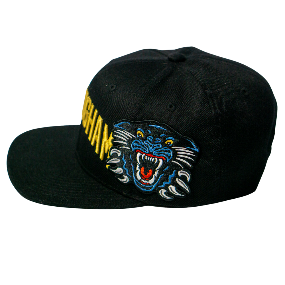 The Panthersland Nottingham Panthers 25-26 Big City Text Snapback Cap is a bold black cap with vibrant yellow text on the front and a colorful embroidered roaring panther on the side.