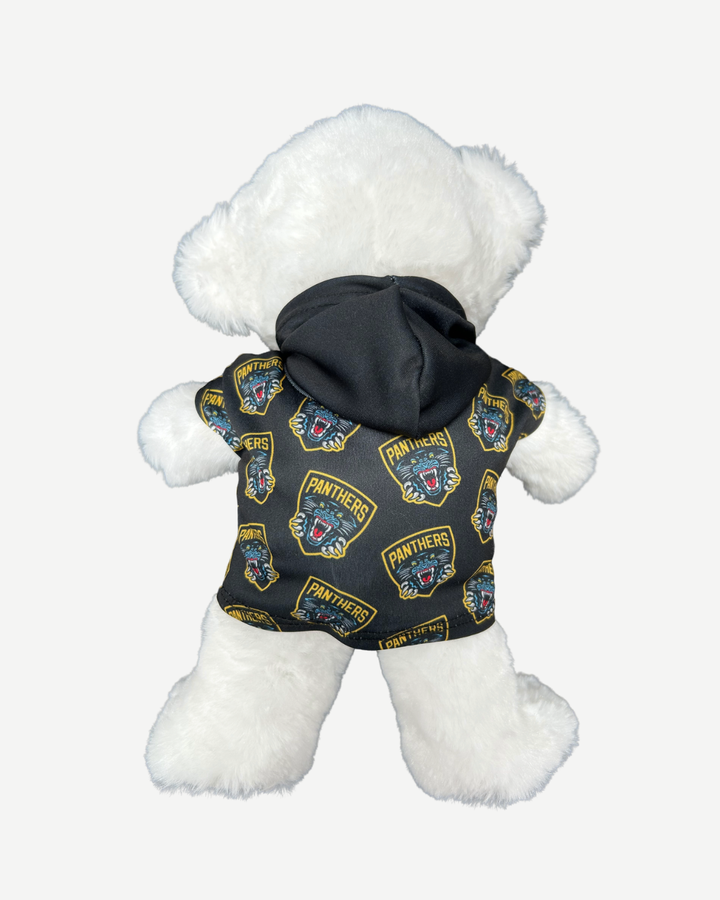 White teddy bear wearing a black jacket with logos on a white background