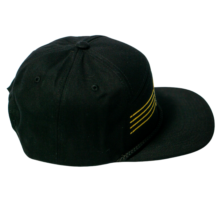 The Nottingham Panthers 25-26 Four Stripe Flatbrim Cap by Panthersland features a black design with four horizontal gold stripes on the front and a braided black band above the brim.