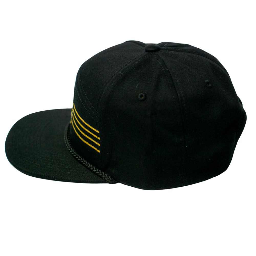 The Panthersland Nottingham Panthers 25-26 Four Stripe Flatbrim Cap is black with four yellow side stripes, gold stripe detail, ventilation eyelets, and a decorative black chain along the brim.