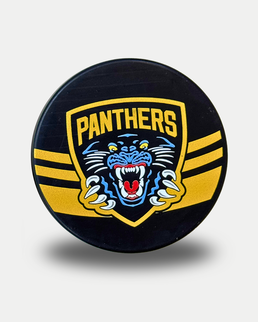 The Panthersland Nottingham Panthers 25-26 Gold Stripe Puck is a black puck with a yellow and black shield, "PANTHERS" text, a roaring blue-accented panther, and two yellow stripes on each side.