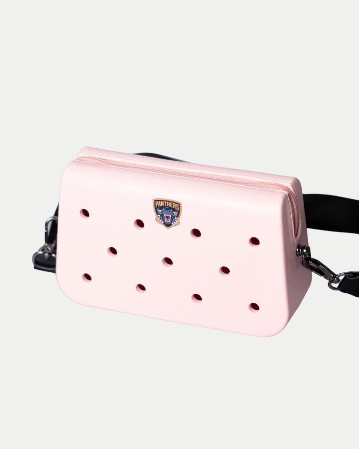 The Nottingham Panthers Croc Charm Bag by Panthersland is a light pink rectangular crossbody with round front holes, a Panthers patch in the center, and a detachable black strap. Shown on a plain white background.