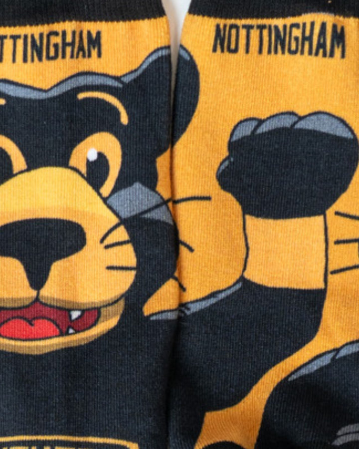 A close-up of Nottingham Panthers Paws Socks by Nottingham Panthers, showing a cartoon black and yellow panther with a raised paw, and NOTTINGHAM boldly printed on the cuff.