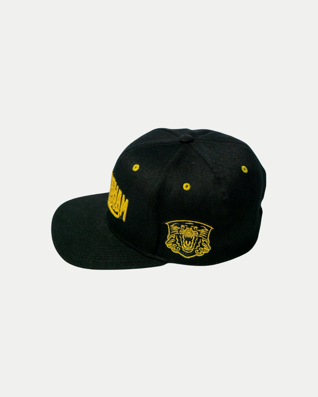 The Panthersland Nottingham Panthers 25-26 Script Snapback Cap is a black baseball cap with gold embroidery, a roaring tiger face on the side, and yellow eyelets on the crown, shown against a plain white background.