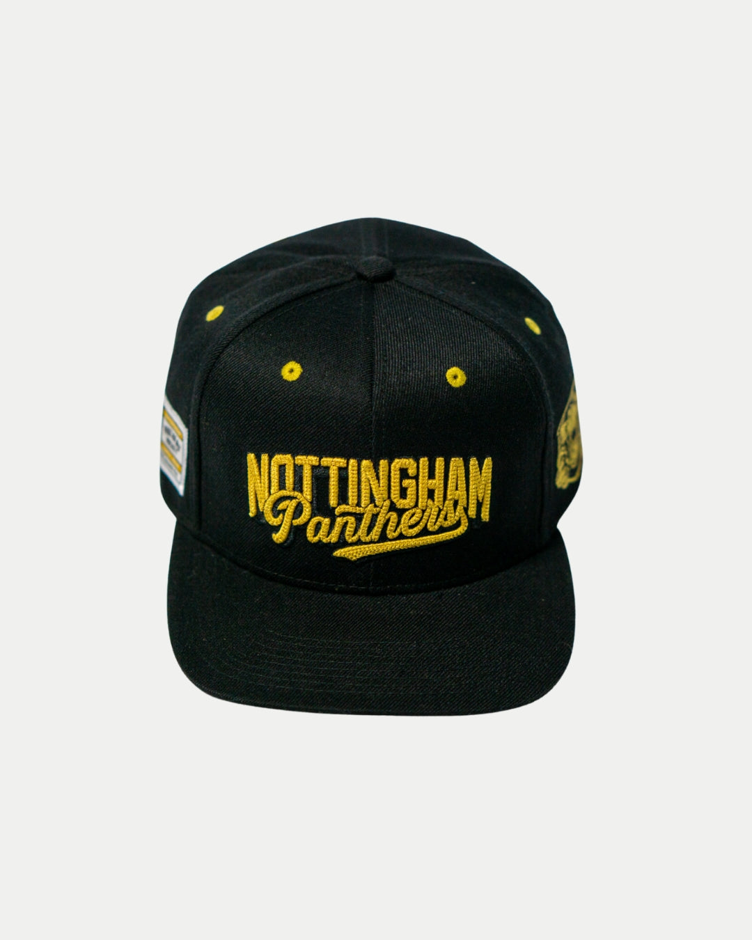 The Panthersland Nottingham Panthers 25-26 Script Snapback Cap features black fabric, gold embroidered script on the front, yellow eyelets, and a side logo patch, shown against a plain light background.