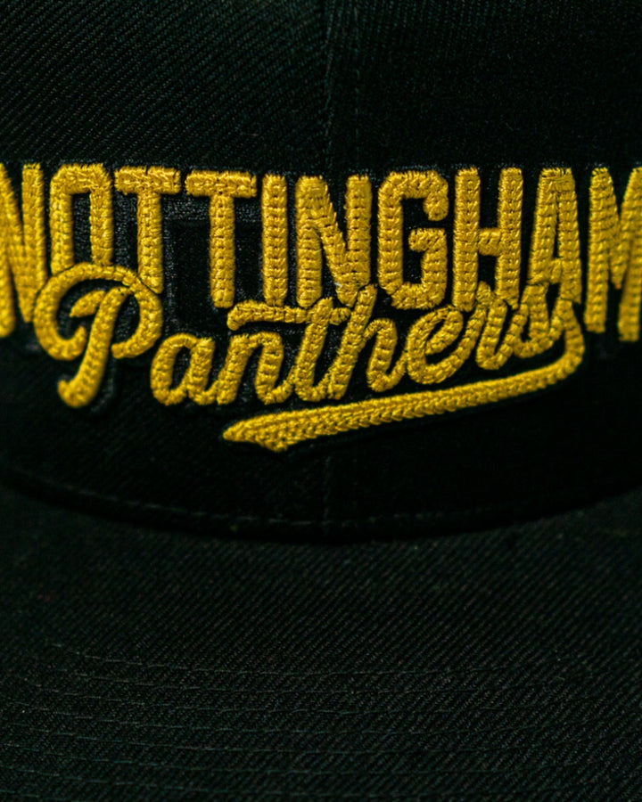 A close-up of the Panthersland Nottingham Panthers 25-26 Script Snapback Cap, a black hat with gold embroidery.