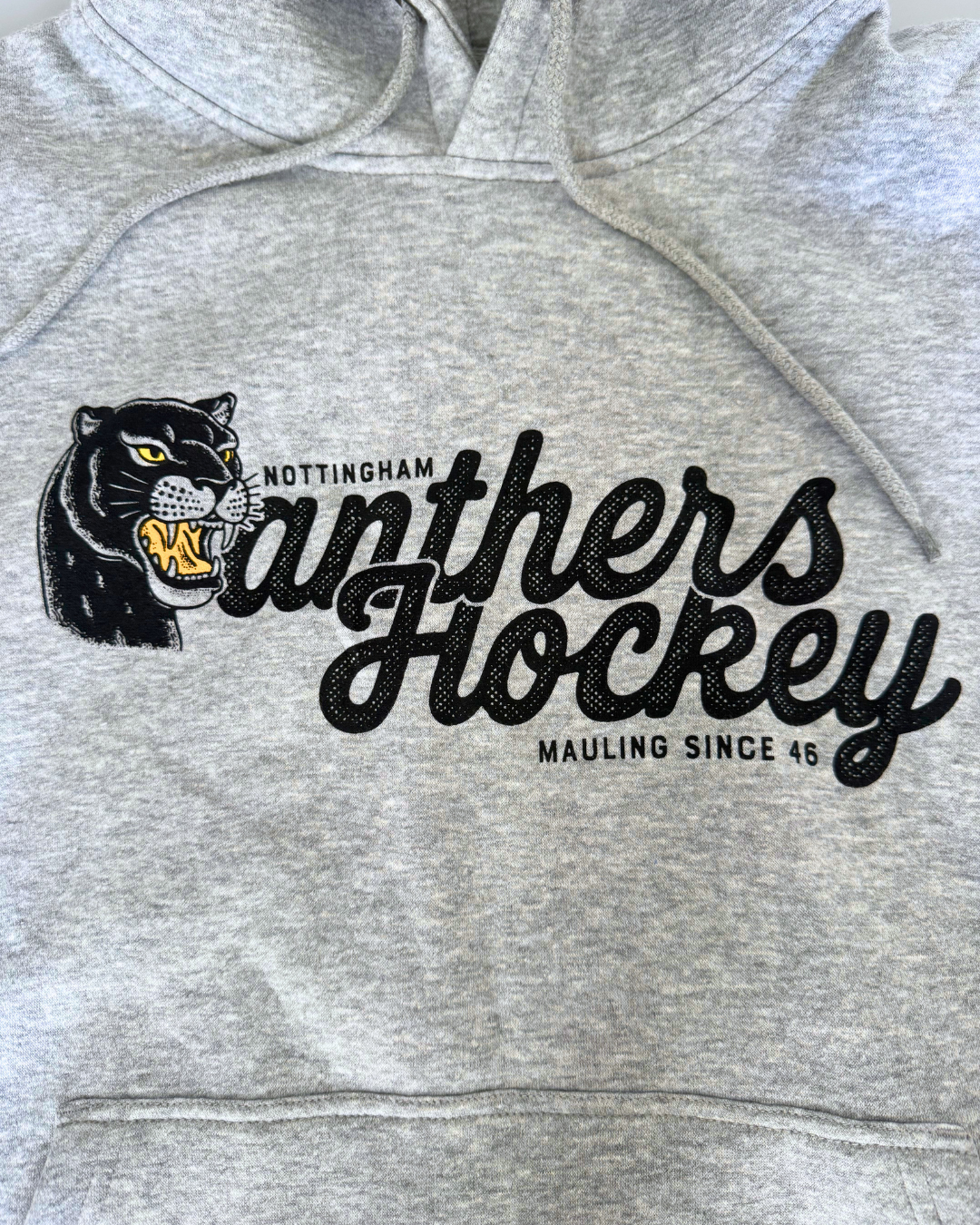 Display your team spirit with the 26-27 Grey Panther Hoodie from Panthersland. This grey hoodie features a bold graphic of a snarling black panther alongside the statement “Nottingham Panthers Hockey, Mauling Since 46” printed on the front—an ideal choice for any devoted Nottingham Panthers hockey fan.