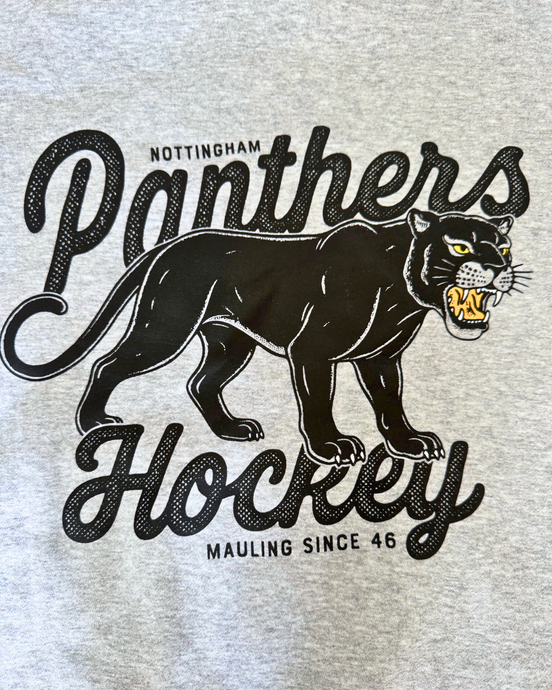 Show your support for Panthers Hockey with the Panthersland 26-27 Grey Panther Hoodie. Featuring a black panther graphic baring its teeth and the text “Nottingham Panthers Hockey Mauling Since 46,” this design is perfect for fans. Also available as a classic grey shirt.