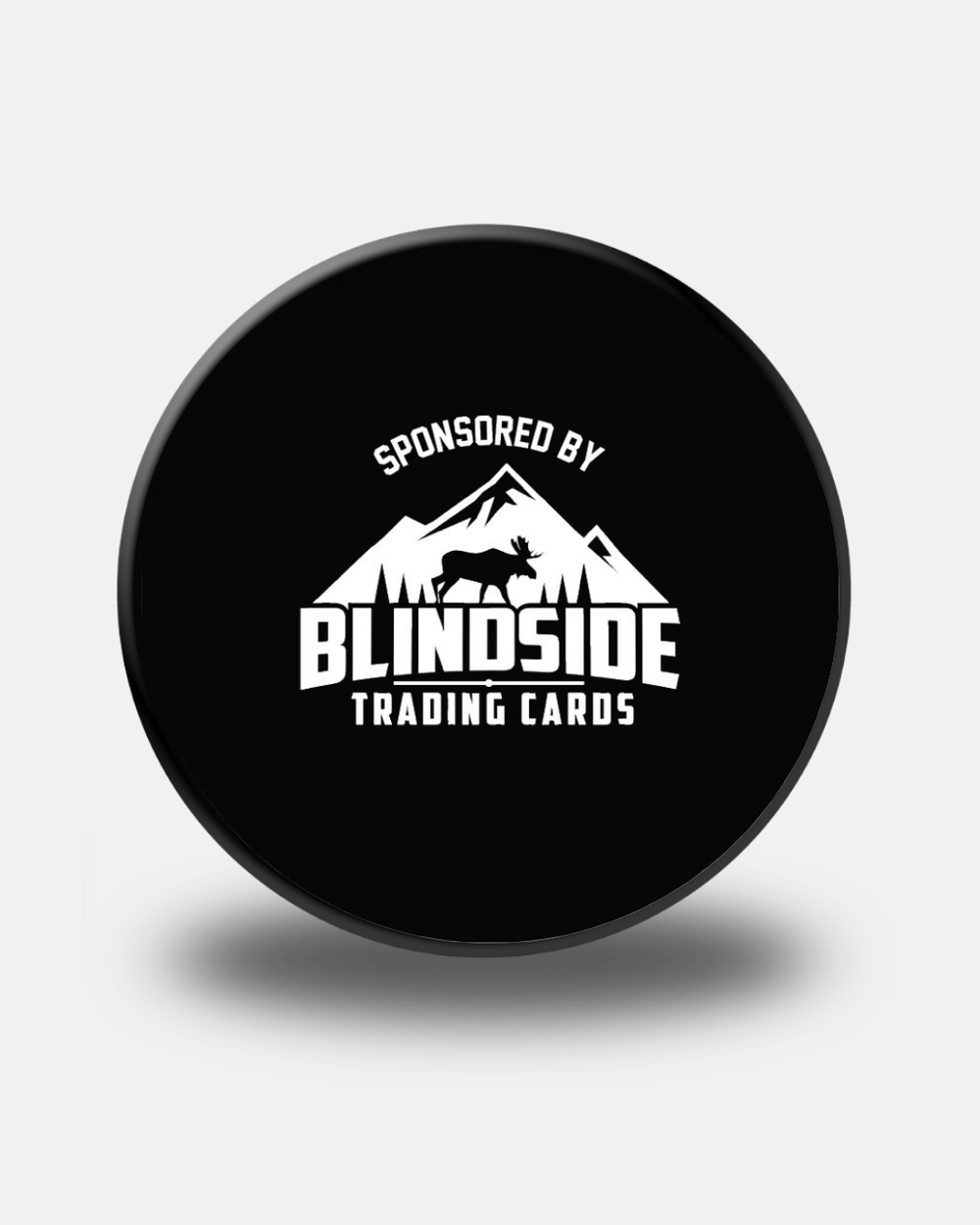 Black Nottingham Panthers Replica Match Puck from Panthersland featuring a logo with mountains, a moose silhouette, and the words “Sponsored by Blindside Trading Cards” in white text. This puck casts a soft shadow on a light background—an ideal addition to any fan’s collection.